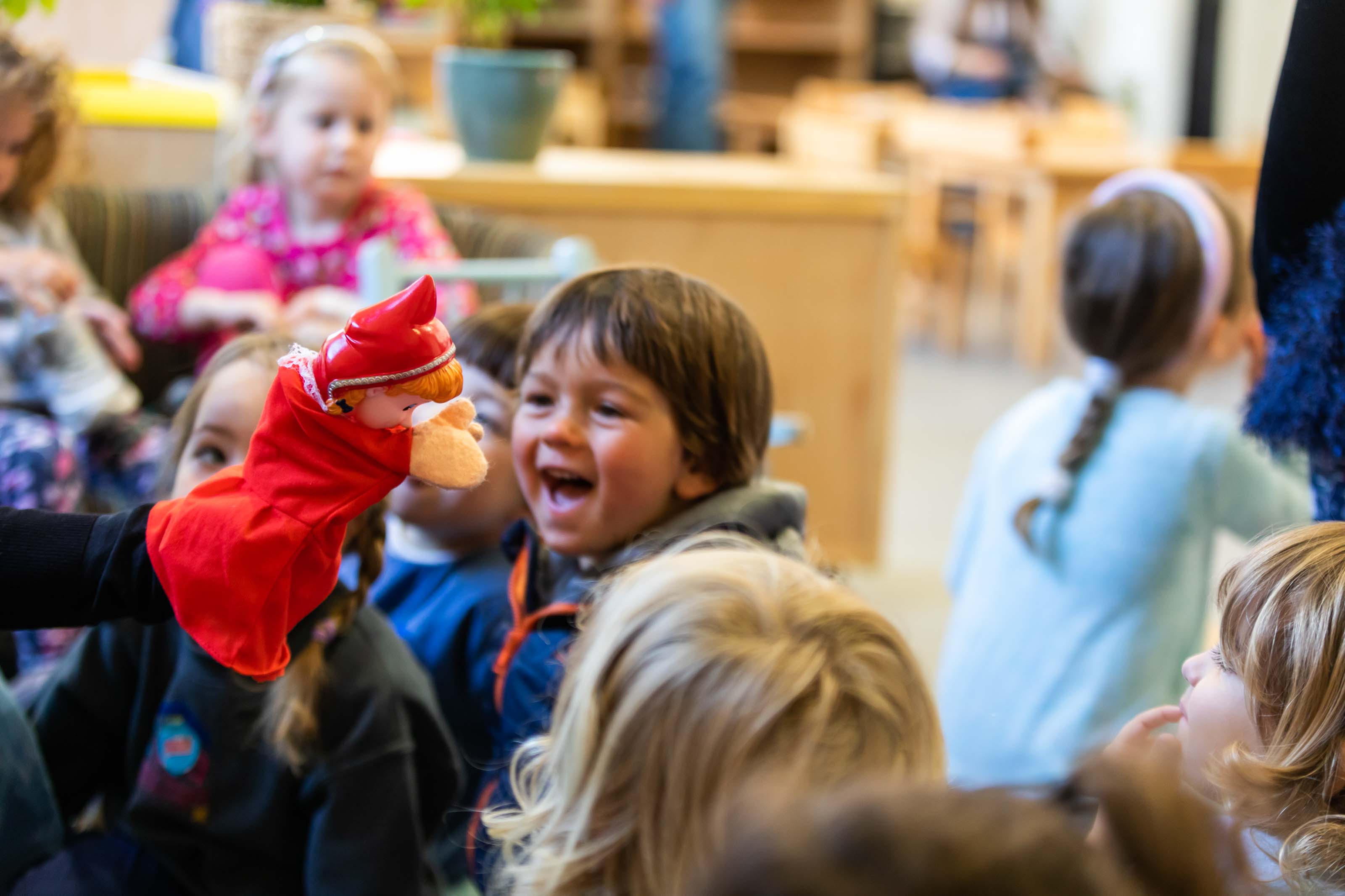 Children laughing at a red puppet during a drama session at Casa Montessori